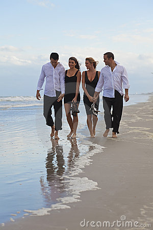 Four Young People Two Couples Holding Hands Looking Out To Sea On A
