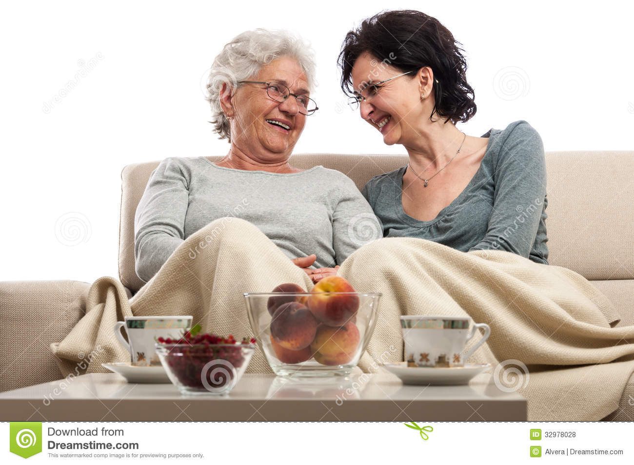 Two Women Sitting In Living Room In Front Of Coffee Table Talking And